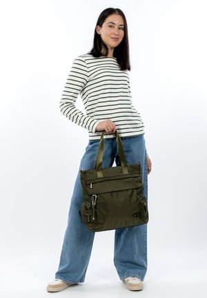 Olivgrüne Tragetasche mit zwei oberen Griffen, Reißverschluss und Druckknopfverschluss, aus strukturiertem Stoff mit Fronttaschen, getragen von einem Modell in gestreiftem Hemd.