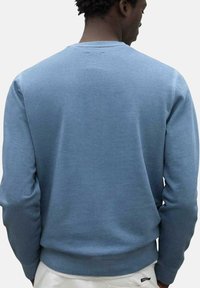 Sudadera de algodón azul con cuello redondo y puños y dobladillo acanalados. Presenta una textura suave y un ajuste relajado.