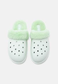 Ζευγάρι λευκών πλαστικών παντοφλών με αμυγδαλωτό πράσινο φλις εσωτερικό και περιλαίμιο, διαθέτοντας πολλαπλές αεραγωγούς στη ζώνη των δαχτύλων.