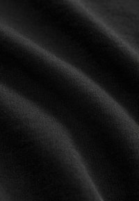 Tessuto nero con una finitura liscia e strutturata, che mostra una leggera rigatura e una sottile lucentezza, catturato in morbide e fluenti pieghe.