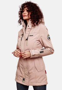 Light pink hooded jacket with zippered pockets, adjustable drawstrings, and logo details on the chest and sleeve; smooth fabric texture.