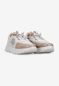 Zapatillas deportivas en tonos beige y blanco con detalles en cuero texturizado, punta redonda y diseño con cordones. Presentan un logo circular en el lado.