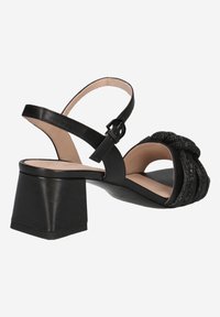 Sandales noires à talon block avec un détail de sangle texturée et boucle à la cheville. Fabriquées en cuir avec une doublure intérieure lisse.