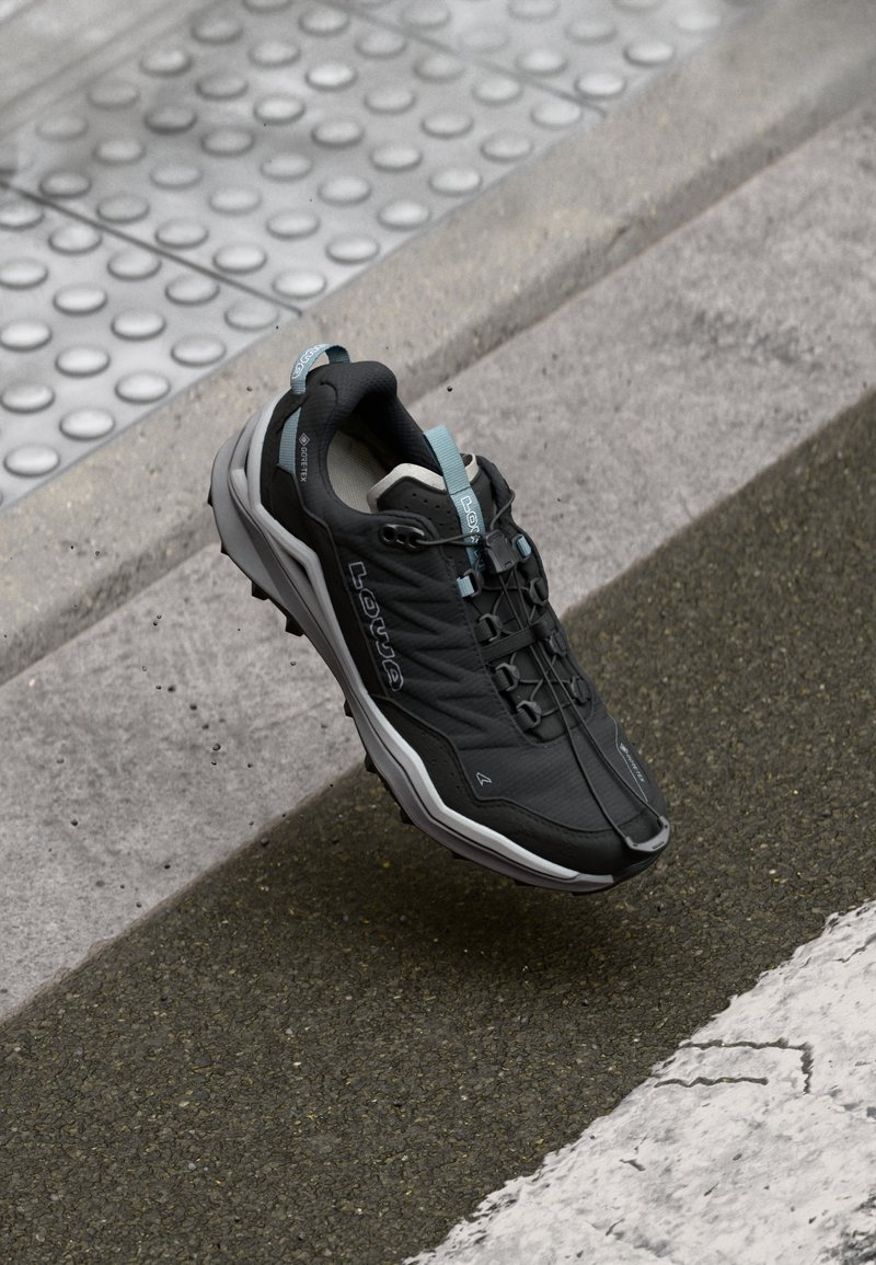 Black hiking shoe with gray accents, textured upper, thin laces, and a rubber sole. Features a loop on the heel for easy wear.