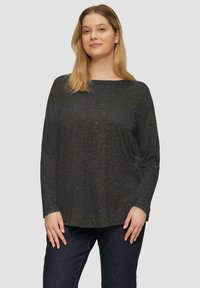 Zwarte lange mouw top van textuurstof met subtiele metallic stippen, voorzien van een brede halslijn en een relaxte pasvorm. Gecombineerd met donkere jeans.