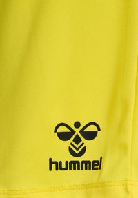 Gul sportströja gjord av syntetiskt material, med en svart logotyp med en bi-liknande design och varumärket "hummel" i fetstil.