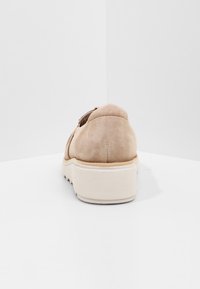 Chaussure slip-on en daim beige avec semelle blanche épaisse, contre un fond blanc uni, vue de l'arrière.