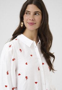 Witte, button-up blouse met rode geborduurde rozen en harten, met een kraag en puffed sleeves in een lichte stof.