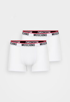 White boxer shorts with a stretch waistband featuring a black and red Moschino logo. Smooth texture; fitted design with short legs.
