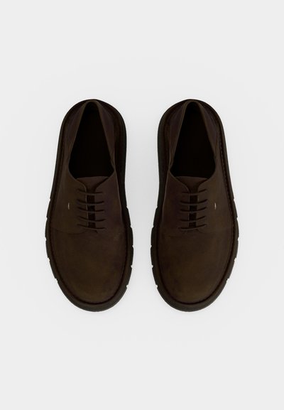 Ζευγάρι σκούρα καφέ δερμάτινα καθημερινά παπούτσια με κορδόνια και μαύρες σόλες, φαίνονται από πάνω πάνω σε λευκό φόντο.