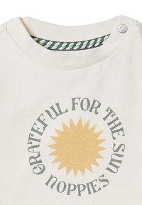 Crème kleurig katoenen T-shirt met een ronde hals, voorzien van een zonafbeelding en tekst in het grijs, met een patroon in de binnennek.