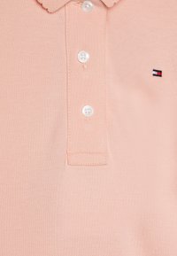 Šviesiai rožinė polo marškinėliai, pagaminti iš tekstūruotos medvilnės. Su sagų apykakle, trimis baltomis sagomis ir mažas siuvinėjimas logotipas.