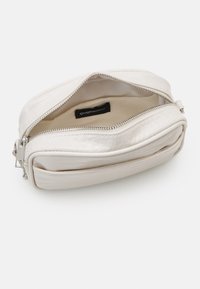 Bílá, texturovaná syntetická taška se zipem a vnitřní etiketou. Otevřený design odhaluje měkkou, béžovou podšívku. Kompaktní, obdélníkový tvar.