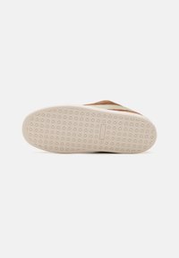 Shoe sole with a textured, patterned surface, light beige color, featuring a smooth, rounded edge and minimal branding detail.