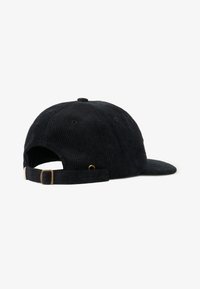 Gorra de pana negra con visera curva, que cuenta con una correa ajustable en la parte trasera y una hebilla de metal. La textura es acanalada con un interior suave.