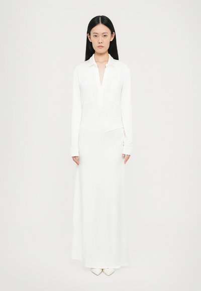 Robe blanche à manches longues avec un décolleté en V, deux poches avant, texture douce et un corsage ajusté qui descend en jupe droite.
