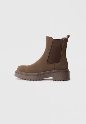 Braune Wildleder-Ankle Boots mit elastischen Seiteneinsätzen, runder Zehenform und einer robusten Gummisohle. Mit einem Ziehband für ein einfaches Anziehen.