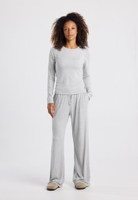 Helles graues Loungewear-Set aus weichem Stoff, bestehend aus einem Langarmoberteil und Freizeithosen mit einem lockeren Schnitt. Strapazierfähiges und bequemes Design.