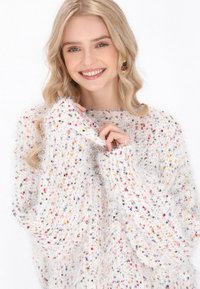 Pulover alb pufos, confecționat dintr-un material texturat, având fire multicolore dispersate pe întreaga suprafață. Design lejer, cu mâneci lungi.