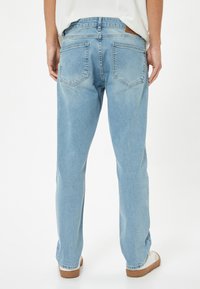 Jeans in denim azzurro con taglio dritto, dotati di due tasche posteriori e di un'etichetta in pelle sulla vita. Texture liscia.
