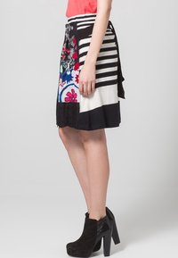 Hame multi-patterned yang menampilkan garis, desain bunga, dan bagian hitam solid. Terbuat dari kain ringan dengan ikatan di pinggang.