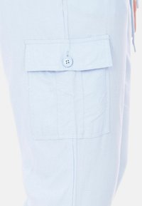 Pantaloni cargo azzurro chiaro con tasca a pattina fissata da un bottone, realizzati in tessuto morbido, con una vestibilità rilassata e una superficie liscia.