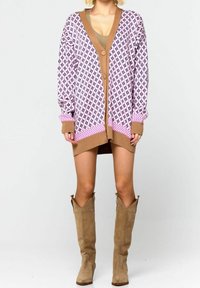 Pletený cardigan s geometrickým vzorem v růžové a hnědé barvě s hlubokým V výstřihem, velkými knoflíky a elastickými manžetami. V kombinaci s hnědými semišovými kozačkami po kolena.