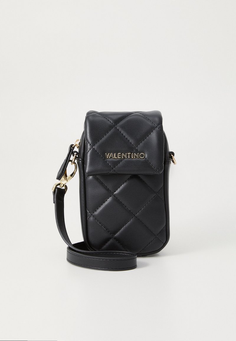 Borsa in pelle trapuntata nera con pattina e logo dorato. Presenta una tracolla removibile e una superficie liscia e lucida. Design compatto per gli essenziali.