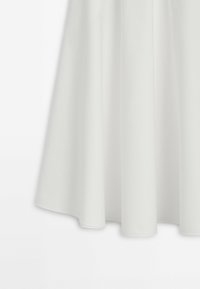 Jupe midi évasée blanche en tissu lisse, dotée d'une taille ajustée et d'un drapé subtil, créant une silhouette fluide. Aucun matériel visible ni motif.