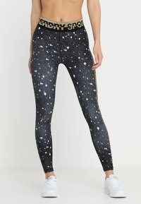 Czarne legginsy z gwiezdnym wzorem, dopasowany krój, złoty pas z logo "Superdry Sport" i długość do kostek.