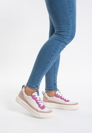 Sportliche Sneakers mit einem weißen Canvas-Obermaterial und pinkem Wildlederakzenten, lebhaften pinken Schnürsenkeln und einer blauen Fersenschlaufe, auf einer weißen Sohle.