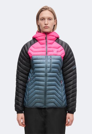 Person with short blonde hair wearing a color-blocked puffer jacket with pink hood, blue torso, and black sleeves, facing forward against plain background.