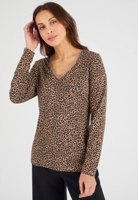 Beige lange mouw top met luipaardprint en zwarte vlekken, met een V-hals voorzien van kant. Zachte stof met een relaxte pasvorm.