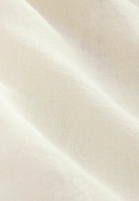 Lichtbeige textielstof met een subtiel geweven patroon. Het oppervlak lijkt zacht en natuurlijk, geschikt voor verschillende textieltoepassingen.