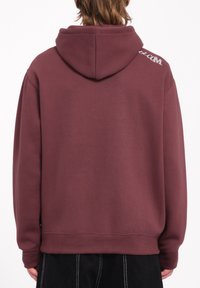 Sudadera capucha color burdeos con un corte relajado, puños y dobladillo acanalados, y un logo impreso en el hombro de la espalda. Mezcla suave de algodón y poliéster.