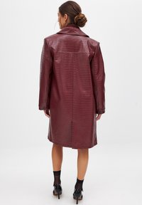 Krokodillenpatroon, diep bordeaux faux leren jas met een prominente kraag, lange mouwen en een rechte snit, gesloten met knopen.
