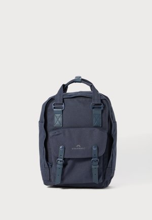 Dunkelblauem Segeltuch-Rucksack mit doppelten Obergriffen, Klappen-Tasche und verstellbaren Trägern. Mit blauen Akzenten und einem Metallsymbol an der Vorderseite.
