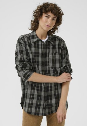 Camicia a quadri bianca e nera con tasca sul petto, maniche lunghe e polsini arrotolati, realizzata in un tessuto leggero.
