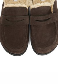 Brown suede slippers with a soft, plush lining. Features a wide strap with cut-out detail and a stitched design along the edges.