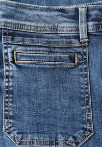 Tessuto denim di colore blu scuro con un design di tasca classico. Presenta cuciture a contrasto e una texture sottile. Vista posteriore dei jeans.