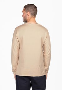 Beige Langarmshirt mit rundem Ausschnitt, weichem Material und lockerer Passform. Verfügt über minimale Nahtdetails an den Schultern.