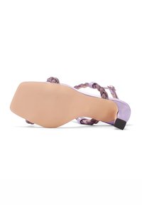 Scarpa con tacco alto color lilla, con tacco quadrato, dotata di cinturini intrecciati e una superficie liscia e lucida. La suola è testurizzata e piatta.