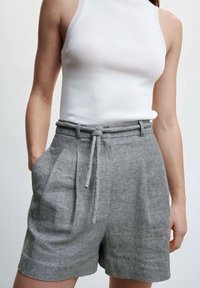 Pantaloni shorts in lino grigio con vita alta, pieghe, tasche laterali e cintura da annodare. Il tessuto presenta una lieve trama e motivo.