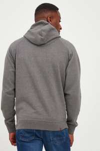 Felpa grigia con cappuccio, caratterizzata da una texture morbida, polsini e orlo a costine, indossata con jeans blu. La vista posteriore mostra i dettagli delle cuciture.