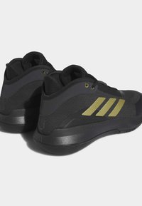 Scarpe sportive nere con una tomaia texturizzata, dettagli dorati e un design elegante. Presentano una suola resistente e un collo imbottito per un maggiore supporto.