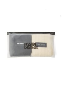 Priehľadná taška obsahujúca dva páry ponožiek; jedny čierne, jedny krémové. Na prednej strane je vytlačené logo "KARL LAGERFELD" v čiernej farbe.