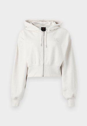Sweatshirt à capuche coupé en beige clair. Tissu doux, zipper à l'avant, poignets côtelés, logo brodé sur le côté gauche de la poitrine.
