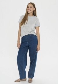 Szary, krótki rękaw t-shirt zestawiony z niebieskimi dżinsami o wysokim stanie i prostym kroju. Stylizację dopełniają beżowe, zdobione baleriny.