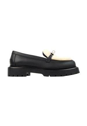 Zwarte leren loafer met dikke profielzool en witte, pluizige bovenband, met een klein zilveren gespje op het bovenwerk.