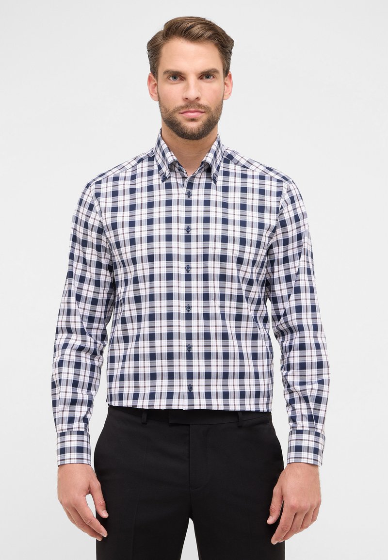 Camicia da uomo con bottoni in un motivo a quadri navy, bianco e azzurro chiaro, con colletto a punte e maniche lunghe, abbinata a pantaloni neri.